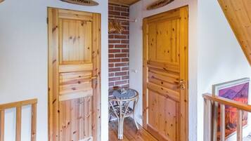 Interior de madera con dos puertas que dicen 'LOMAK AMMAR I' y 'PERAKAMMAR I', una pequeña mesa y una pared de ladrillo.