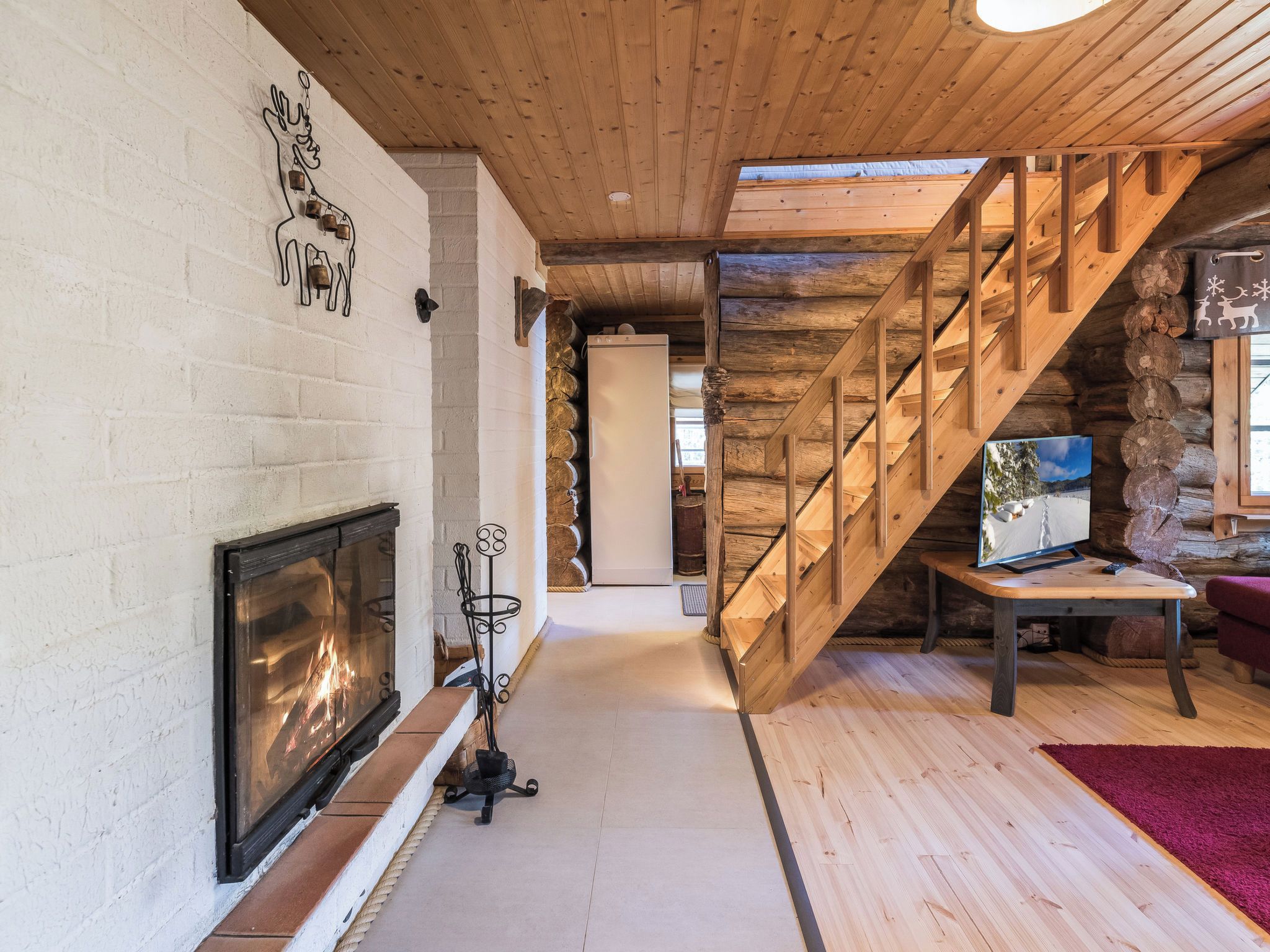 A wooden interior with a fireplace, a staircase, and a television on a wooden table.