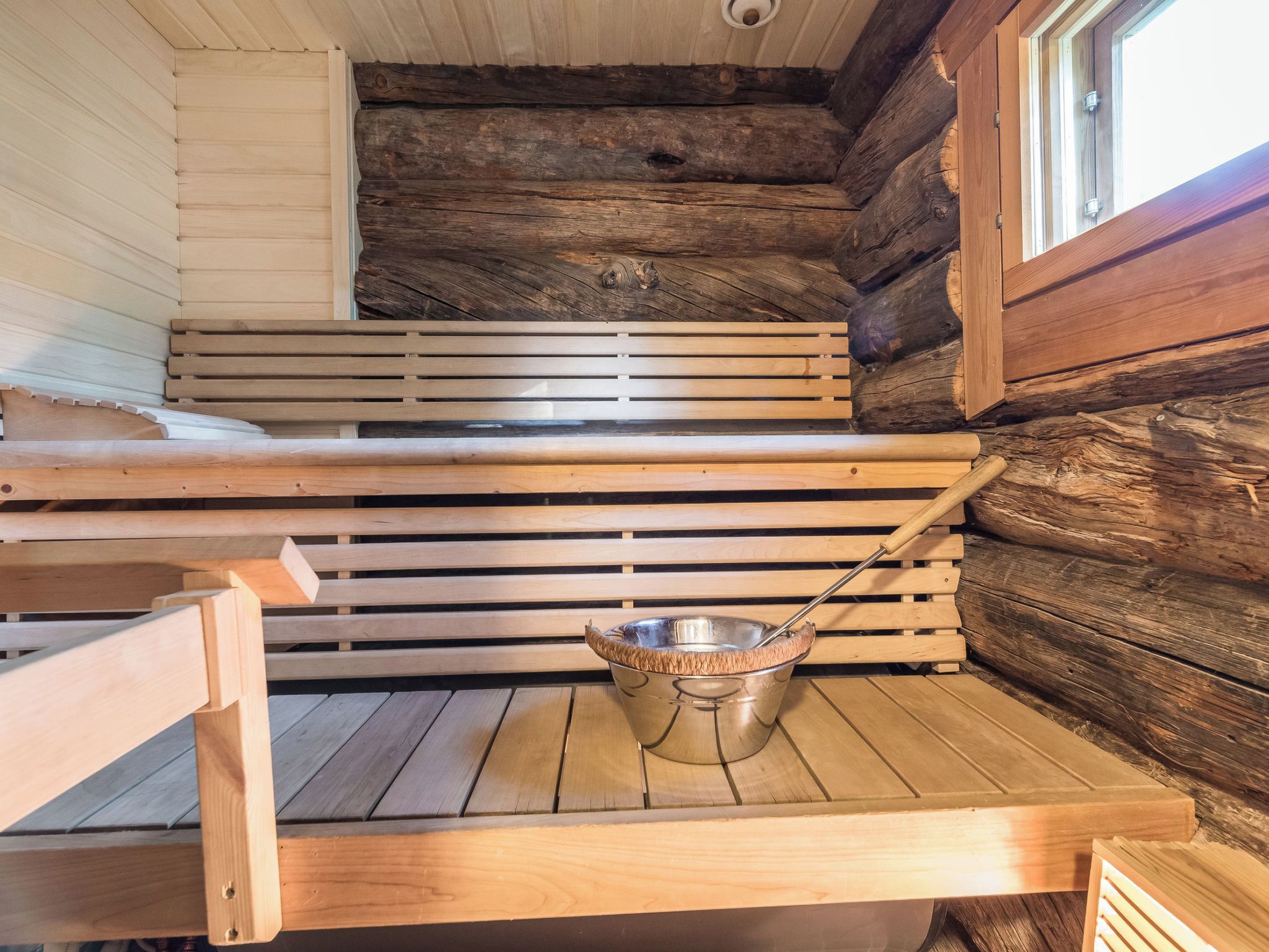 En sauna med træbænke og en metalvask.