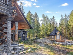 A rustic cabin with a stone foundation and wooden exterior, surrounded by a forest. - Lomaperä by Interhome (Ylläsjärvi)