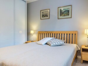 Un dormitorio con una cama, dos lámparas de noche y dos cuadros en la pared.