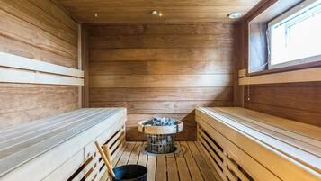 Eine Sauna mit Holzbänken und einer zentralen Heizvorrichtung.