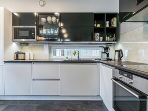 Een moderne keuken met een magnetron, oven en koffiezetapparaat.