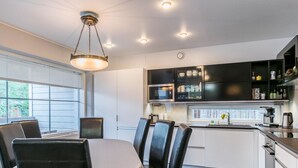 Une cuisine moderne avec des meubles blancs, un plan de travail noir et un coin repas comprenant une table et des chaises.
