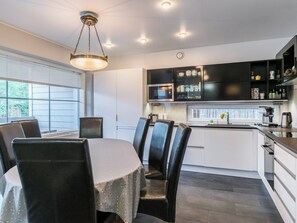 Una cocina moderna con comedor, que incluye una mesa redonda con sillas, horno empotrado y cafetera.