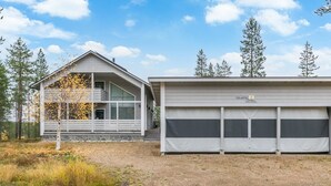 Une maison à deux étages avec un garage, entourée d’arbres et dotée d’une allée gravillonnée.