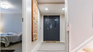 Un couloir avec un lit, un tapis coloré et une porte sombre.