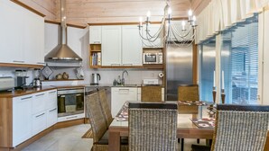 Una cocina moderna con armarios blancos, un refrigerador de acero inoxidable, horno empotrado y una lámpara colgante.
