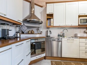 Une cuisine moderne avec des armoires blanches, des appareils en acier inoxydable et un plan de travail en bois.
