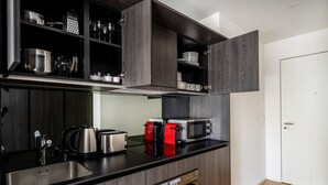Une cuisine moderne avec des meubles en bois foncé, des appareils électroménagers en acier inoxydable et un plan de travail noir.