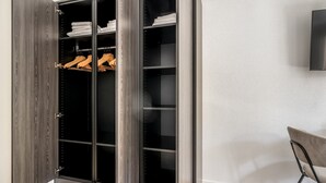 Un dressing avec de nombreuses étagères et un espace pour suspendre les vêtements, un plancher en bois et une chaise placée dans un coin.