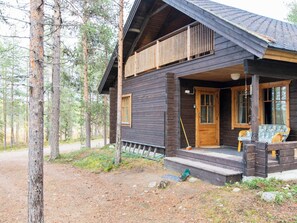 Een chalet met veranda, houten gevel en uitzicht op het omliggende bos.