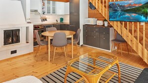 Une cuisine moderne dotée d’une cuisinière intégrée, d’un coin repas avec des chaises et d’un téléviseur fixé à un mur en bois.