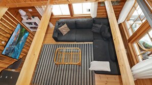 Un intérieur de chalet chaleureux avec un canapé d’angle, une petite table et un téléviseur.