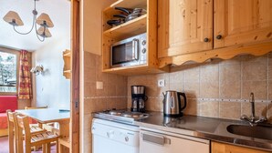 A compact kitchen with wooden cabinets, a microwave, a coffee maker, and a dishwasher. - Studio 4 ppl near the ski runs, ski lifts at 50m (Doucy)