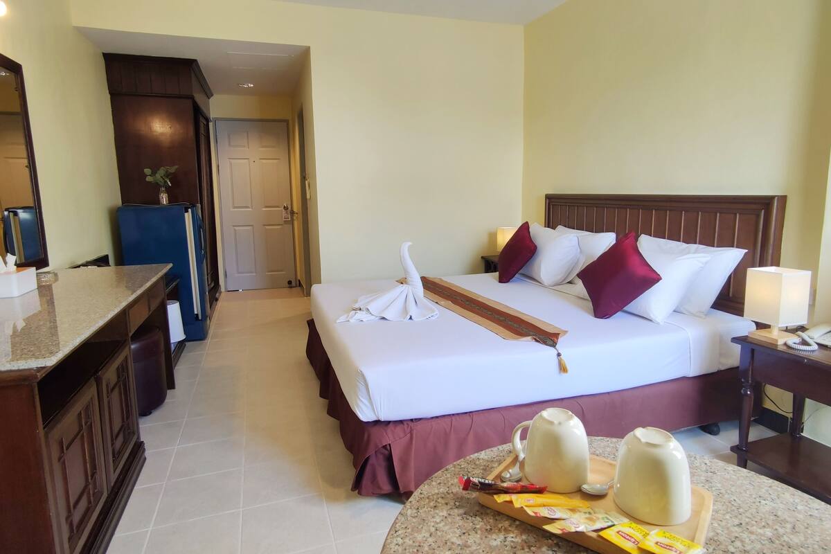 Une chambre d’hôtel comprenant un lit, une table de chevet, une petite table et un coin cuisine avec un réfrigérateur et un évier.