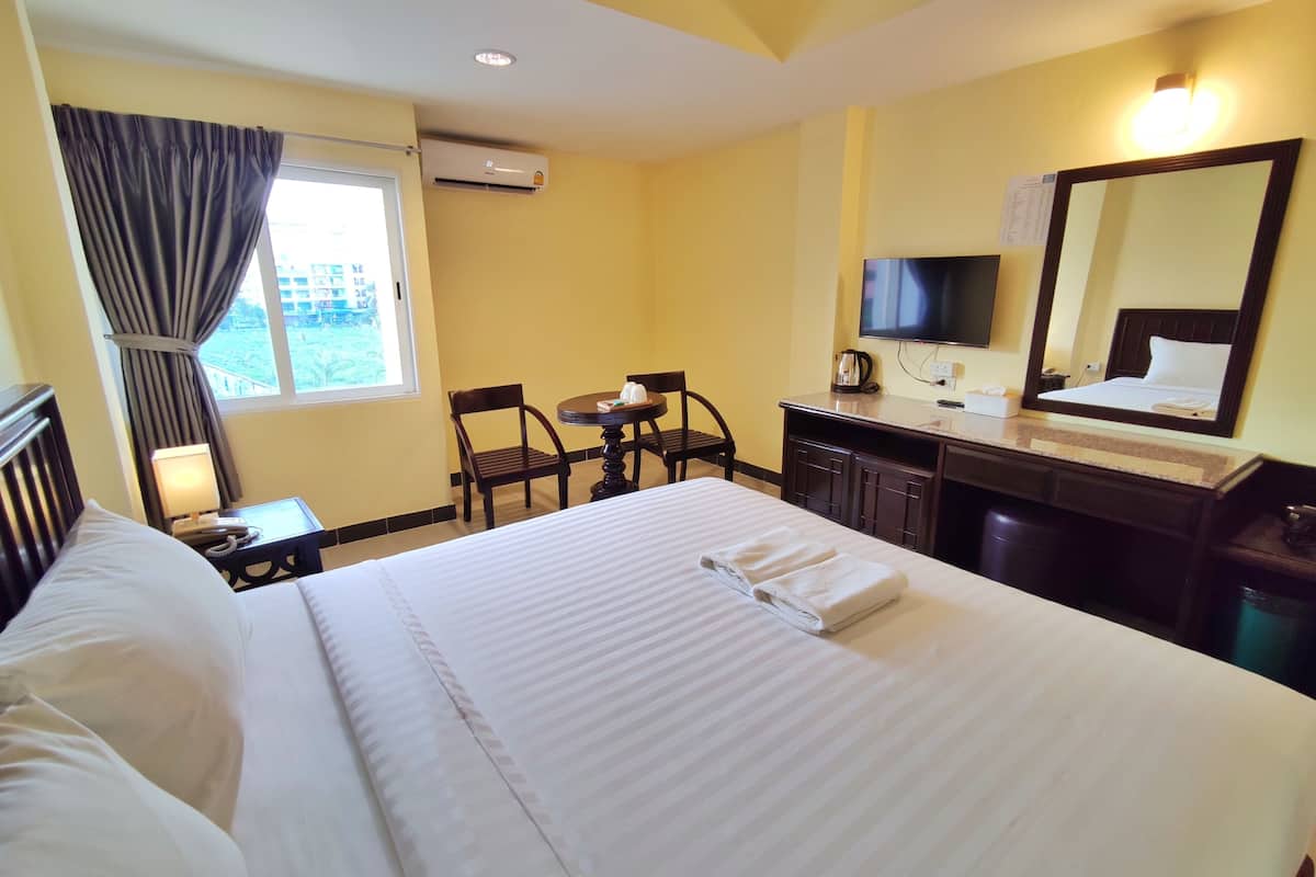 Une chambre d’hôtel équipée d’un lit, d’un bureau, d’une chaise, d’une télévision et d’un appareil de climatisation.