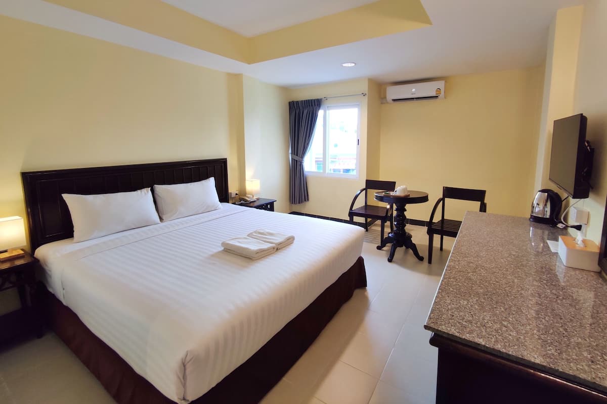 Une chambre d’hôtel avec un grand lit, un bureau avec une chaise, une télévision et un appareil de climatisation.