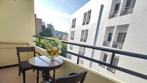 Ein Balkon mit rundem Tisch, zwei Stühlen und einer Blumenvase.