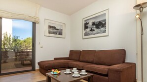 A modern living room with a brown sofa, a wooden coffee table, and two framed black and white photographs on the wall.