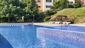 A swimming pool with clear blue water, surrounded by trees and modern buildings.