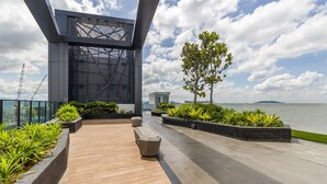 A modern outdoor terrace with a wooden floor, concrete pathways, and planters with greenery. - Continew Residensi by Airhost  (Kuala Lumpur)