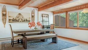 A dining area with a wooden table, bench, and chairs, a rug, and a window with a view of trees. - Private Hot Tub _ Pet Friendly _ 2 Living Rooms + Kitchen & Kitchenette (Vail)
