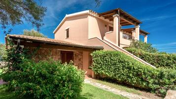 Una casa de dos pisos con fachada de piedra, un balcón de madera y un camino de piedra que lleva a la entrada.