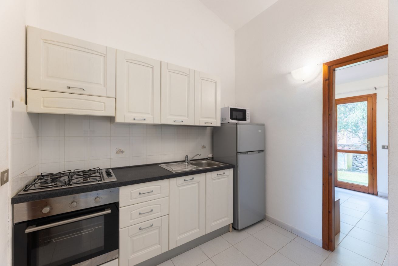 Eine Küche mit weißen Schränken, einem Gasherd, einem Backofen, einer Spüle, einer Mikrowelle und einem Kühlschrank.