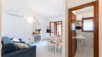 Ett kompakt bostadsutrymme med en soffa, ett matbord, ett köksområde och ett badrum.