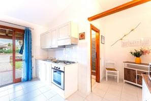 A compact kitchen with white cabinets, a gas stove, and an oven. - Residenze Gallura, three-room apartment 4 beds with air conditioning (San Teodoro)