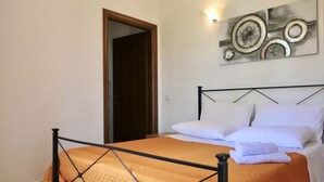 Een slaapkamer met een bed, een deur en een kunstwerk aan de muur.