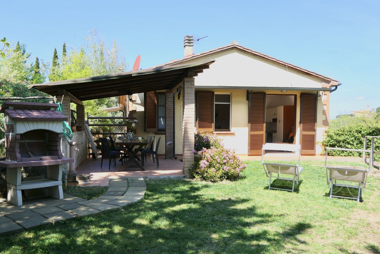 Ein Haus mit Terrasse, Gartenmöbeln und Grill.