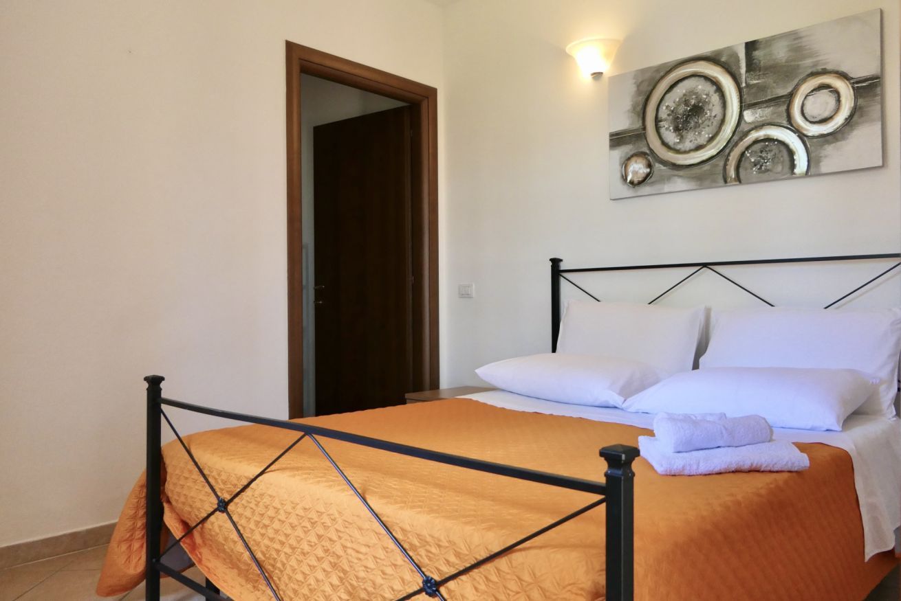 Een slaapkamer met een bed, een deur en een kunstwerk aan de muur.