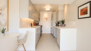 Une cuisine moderne avec des meubles blancs, un îlot central et un coin repas comprenant une table et des chaises blanches.