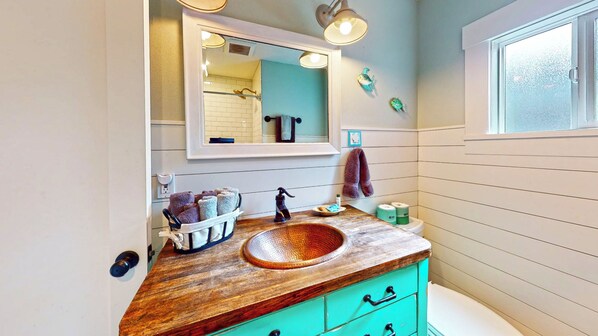 Une salle de bain avec un meuble-lavabo en bois, un grand miroir, un évier et une fenêtre.