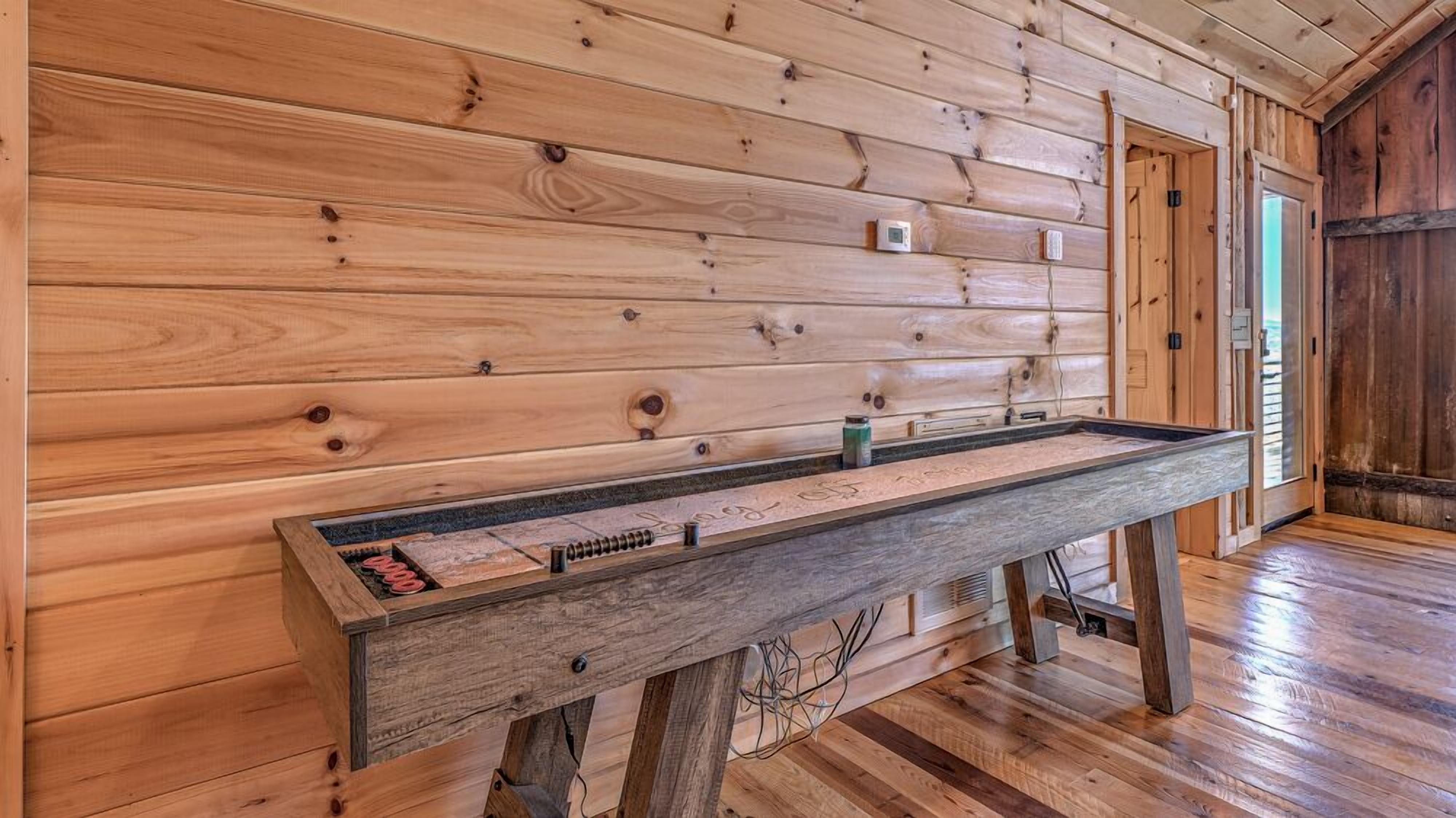 Une table en bois dotée d’un cadre en métal, placée contre un mur en bois dont on peut voir les nœuds et les motifs du grain.