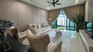A modern living room with a sofa, armchairs, a coffee table, and a TV. - Legasi Kampung Bharu Guesthouse (Kuala Lumpur)