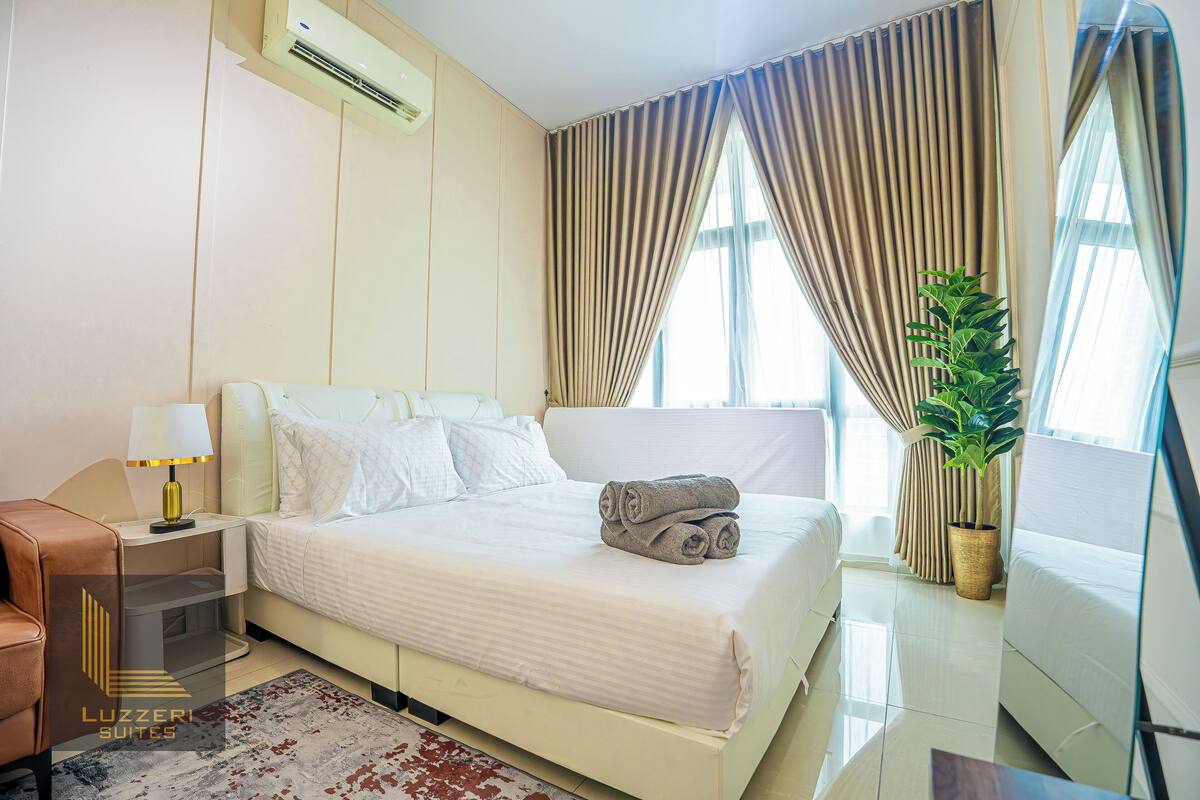Une chambre d’hôtel avec un lit, une table de chevet, une lampe et une plante en pot.