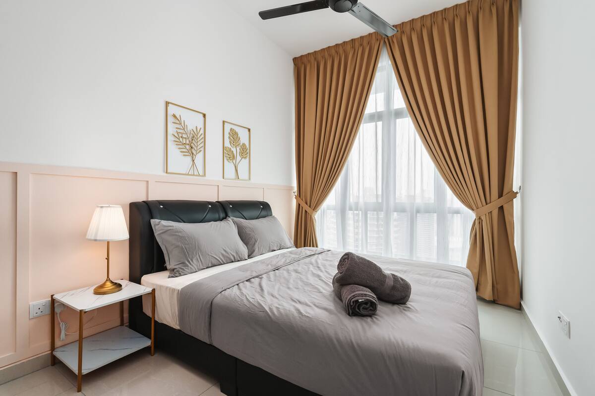 Un lit bien fait, avec un oreiller, une table de chevet avec une lampe et un ventilateur de plafond.