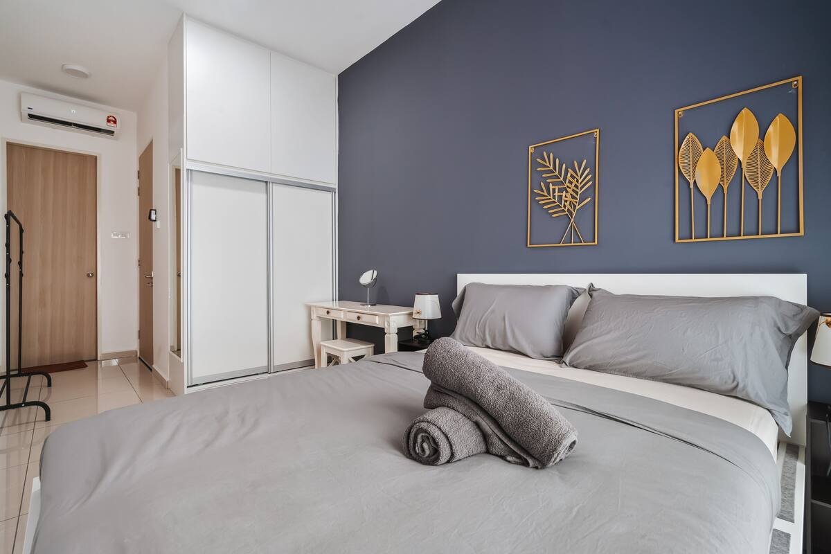 Une chambre moderne avec un grand lit, un bureau et deux œuvres d’art accrochées au mur.