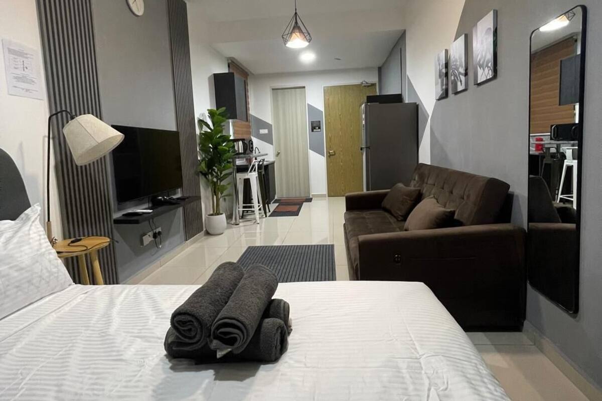 Une chambre d’hôtel moderne équipée d’un lit, d’un canapé, d’une télévision, d’un bureau et d’une plante.