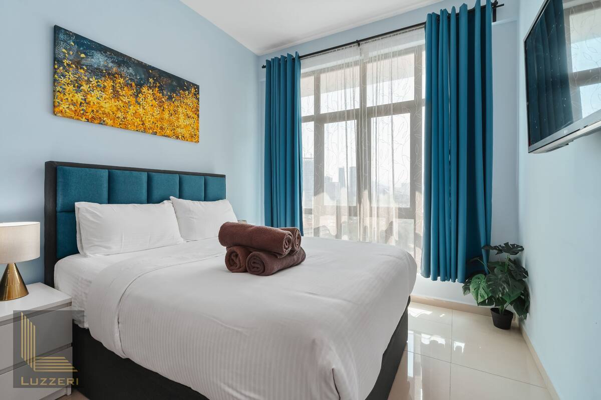 Une chambre d’hôtel avec un grand lit, un tableau au mur et une fenêtre avec des rideaux.