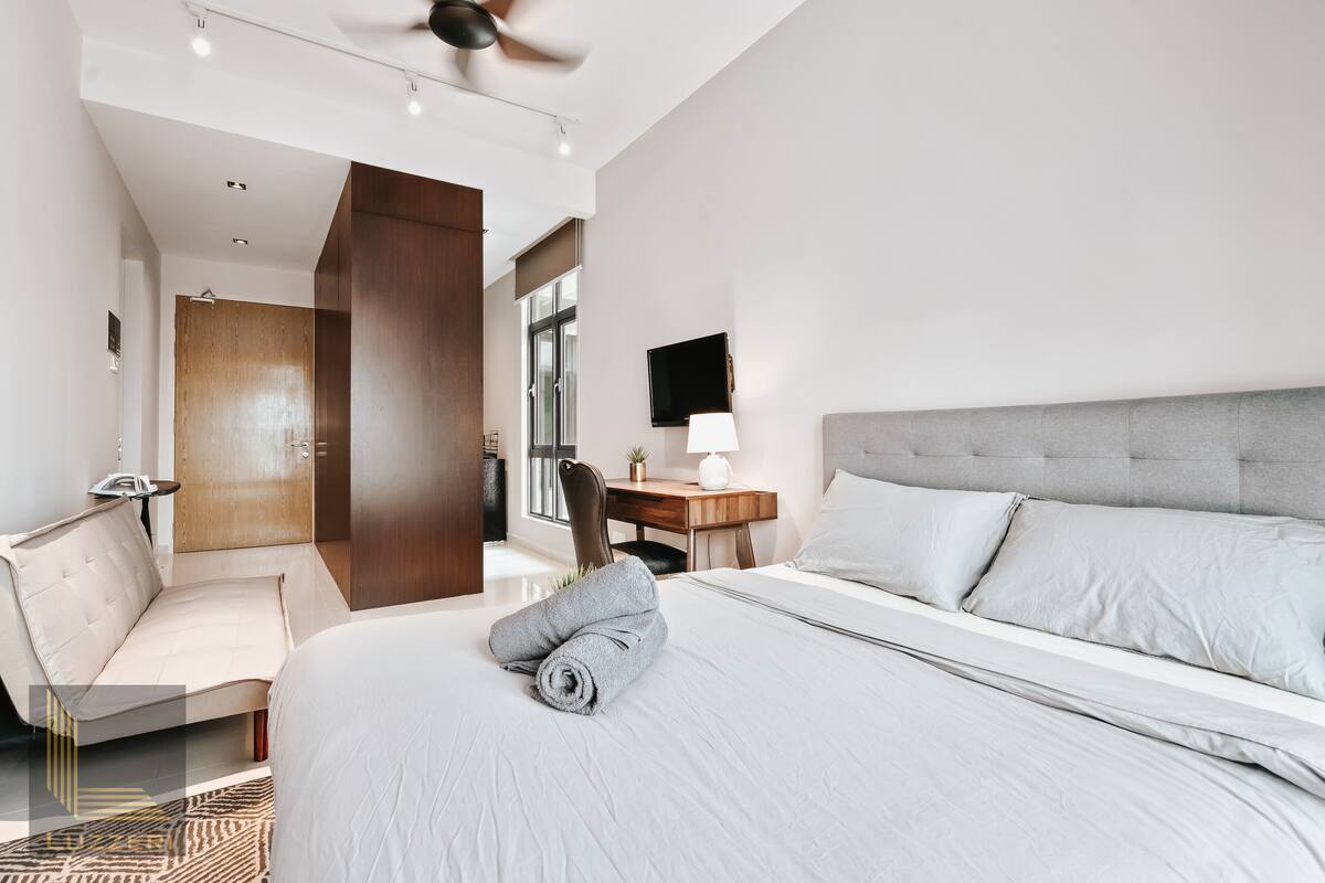 Une chambre d’hôtel moderne équipée d’un grand lit, d’un bureau, d’une chaise, d’un ventilateur de plafond et d’une télévision.