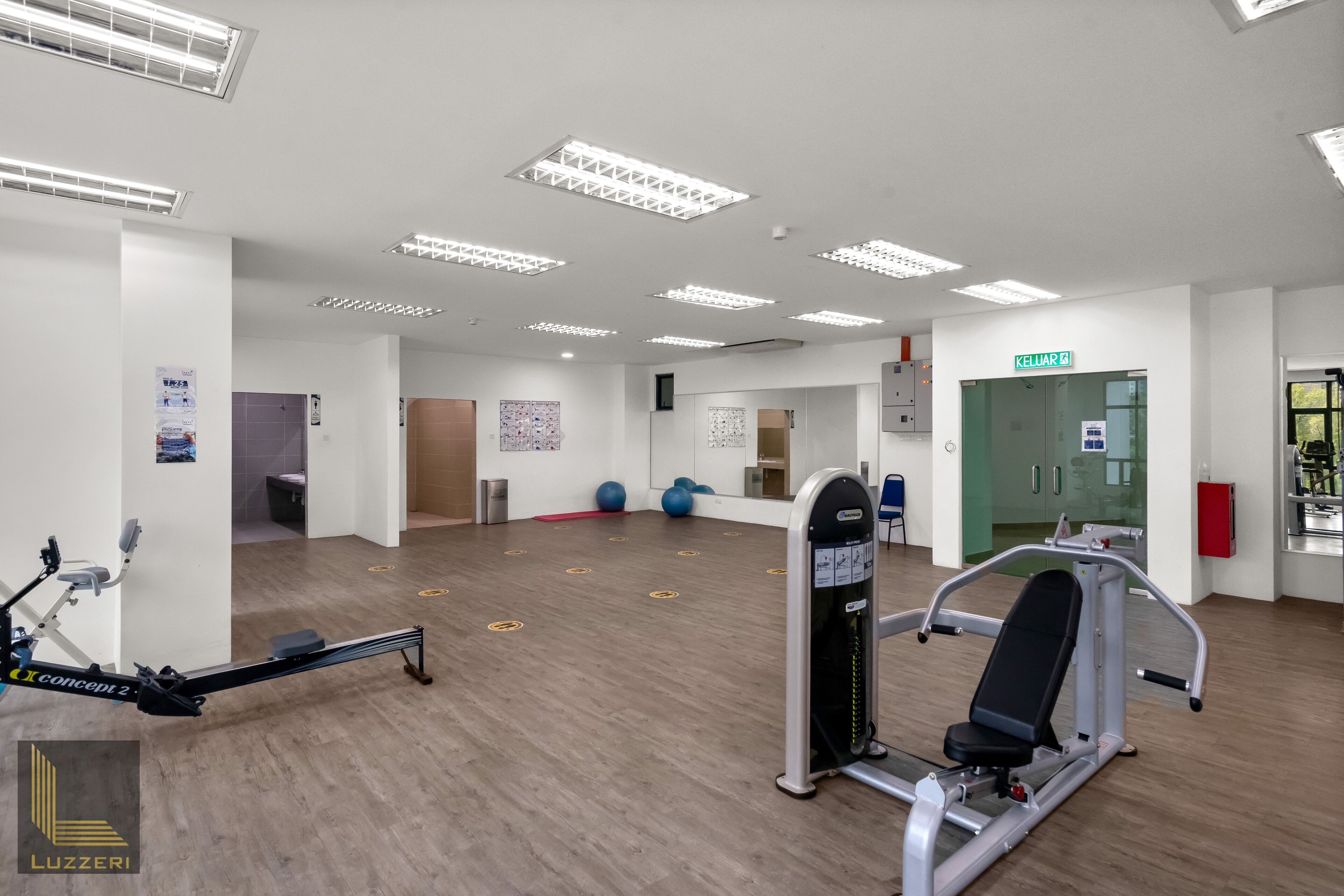 Un gimnasio con equipo de ejercicio, un espejo y una puerta con la etiqueta 'KELVAR'.