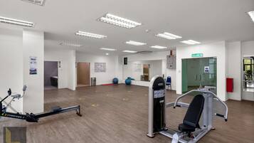 Un gimnasio con equipo de ejercicio, un espejo y una puerta con la etiqueta 'KELVAR'.