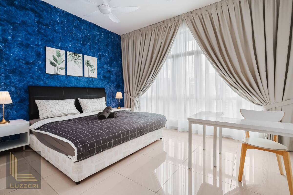 Une chambre moderne avec un grand lit, un bureau blanc et un ventilateur de plafond.