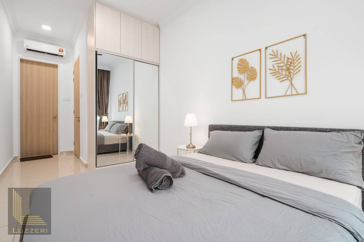 Une chambre moderne avec un grand lit, une armoire, un miroir et deux œuvres d’art représentant des feuilles, encadrées et accrochées au mur.