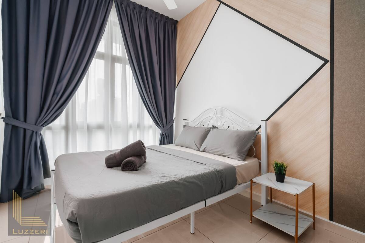 Une chambre à coucher moderne avec un lit, des rideaux, une table de chevet agrémentée d’une plante et un motif géométrique sur le mur.