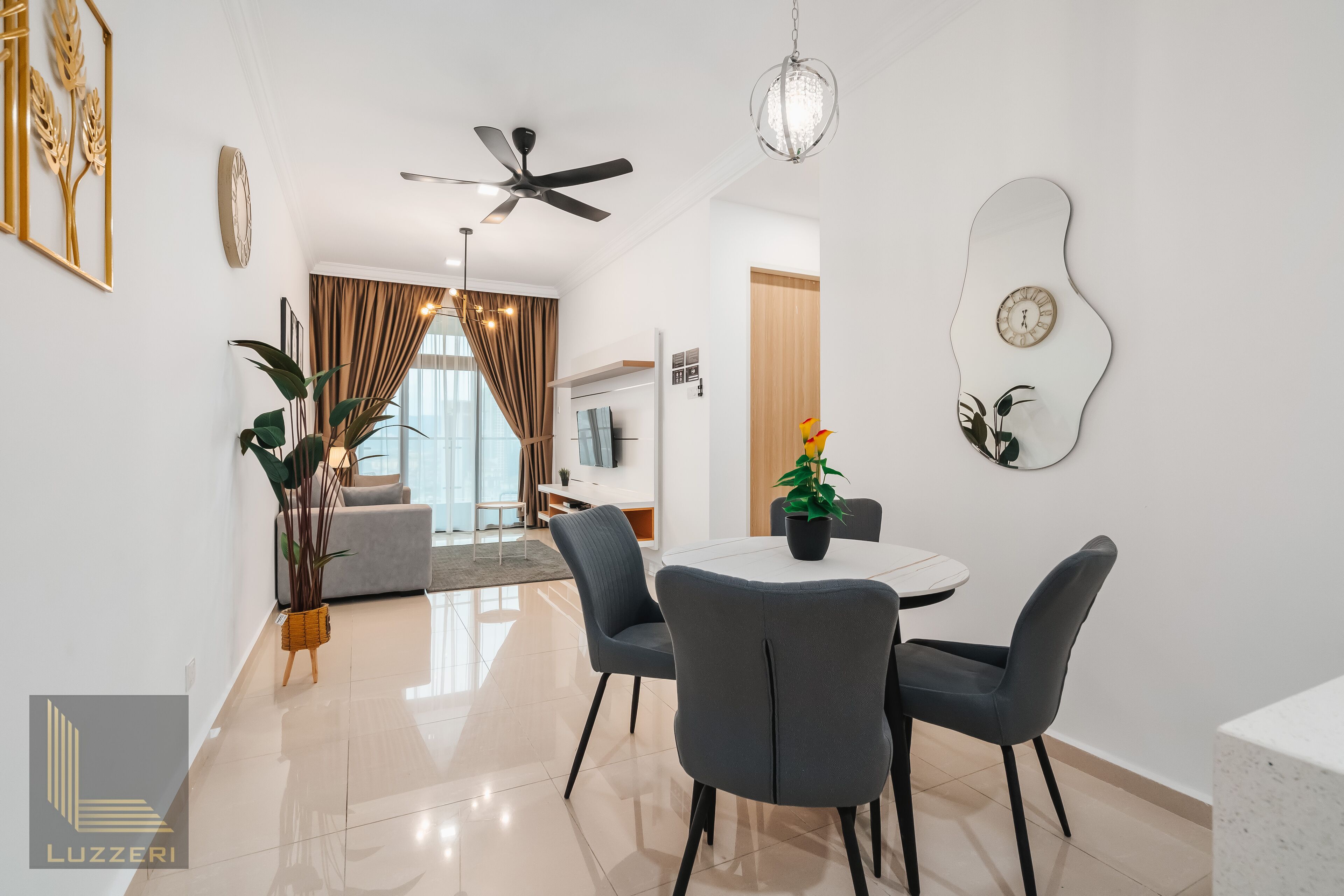A modern dining area with a round table, four grey chairs, and a ceiling fan.
